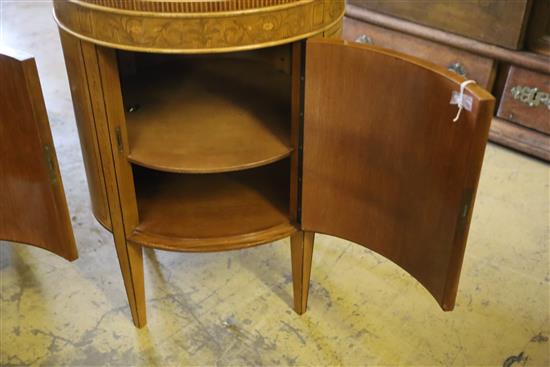 A pair of Edwardian inlaid satinwood bedside cupboards of oval form, decorated with cupid panels, W.51cm, H.73cm